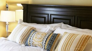 A neatly made bed with white bedding and patterned pillows, a bedside lamp, and a round mirror on the wall. - Temecula Wine Country Guest House w/Kitchen - Prime Location (Temecula)
