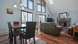 Un salón amplio con mesa de comedor de madera, sofá de cuero y chimenea.