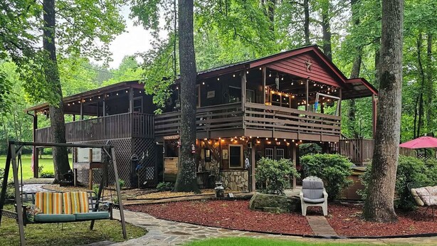 A rustic cabin with a deck, surrounded by trees. - Relax at Clear Creek Family Retreat – Cozy Ellijay Cabin by the Water (Ellijay)