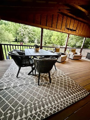 An outdoor deck with a wooden table and chairs, surrounded by a patterned rug. - Relax at Clear Creek Family Retreat – Cozy Ellijay Cabin by the Water (Ellijay)