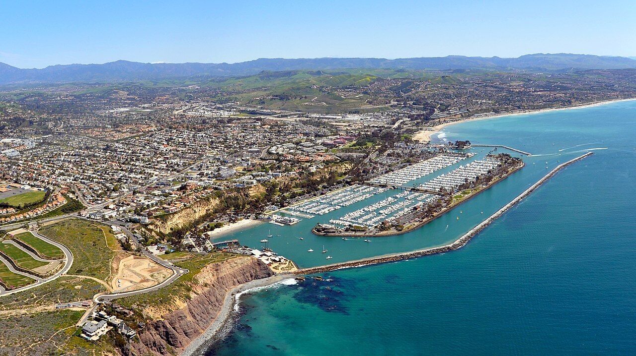 An aerial view of a coastal city with a marina, residential areas, and a prominent coastline.