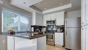 A modern kitchen with white cabinetry, stainless steel appliances, and a granite countertop. - Dana Point Vacation Rental Close To The Beach! (Dana Point)