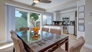 A modern kitchen with white cabinets, stainless steel appliances, and a dining area with a glass table and chairs. - Dana Point Vacation Rental Close To The Beach! (Dana Point)