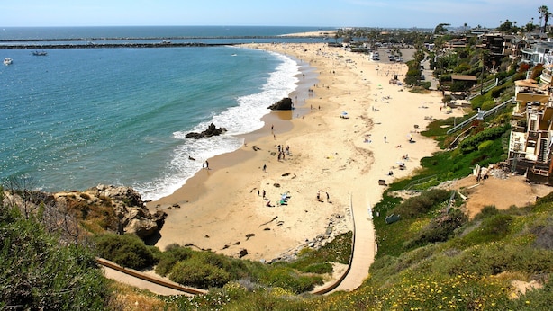 A coastal beach with a paved walkway, beachgoers, and a rocky outcrop. - Dana Point Vacation Rental Close To The Beach! (Dana Point)
