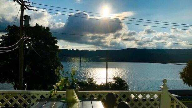 A wooden deck with a view of a lake and mountains. - Charming home with stunning lake views! (Watkins Glen)