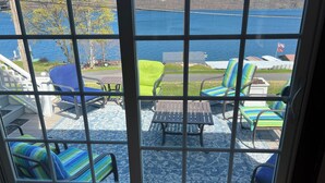 A patio with outdoor furniture, a view of a lake, and a distant hill. - Charming home with stunning lake views! (Watkins Glen)