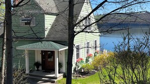 A two-story house with a green roof and a front porch. - Charming home with stunning lake views! (Watkins Glen)