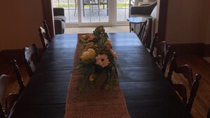 A long dining table with a woven runner, chairs, and a hanging light fixture. - Charming home with stunning lake views! (Watkins Glen)