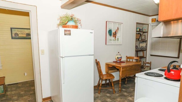 A compact kitchen with a refrigerator, a stove, and a dining table with chairs.