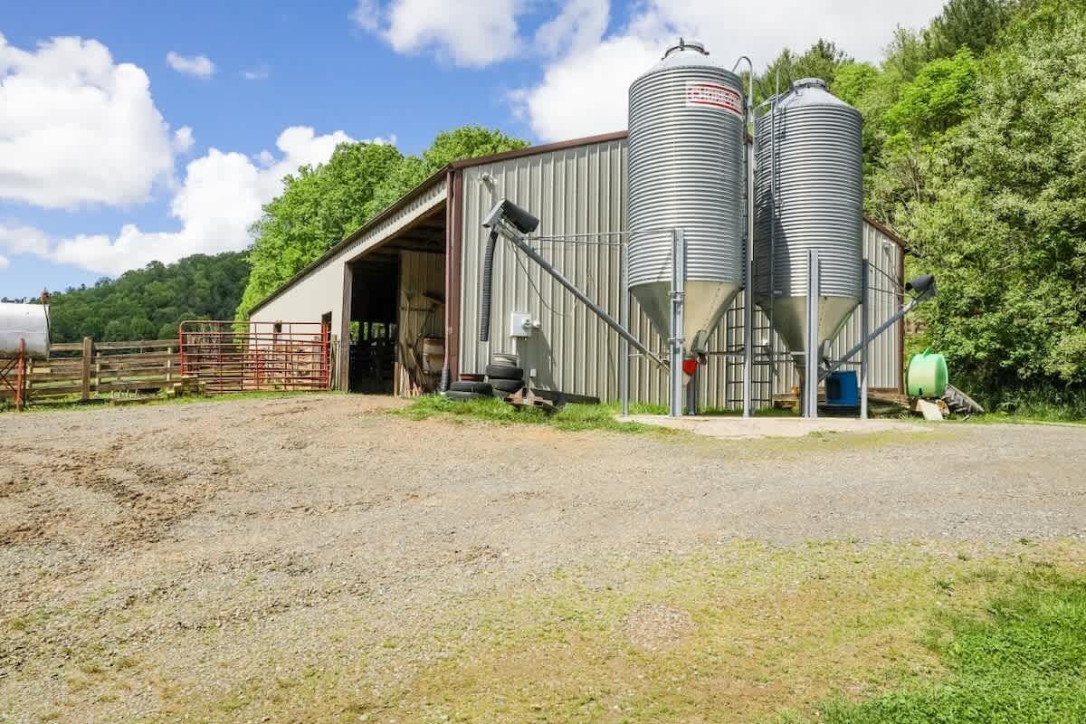 En gård med to store silos, et lade og et indhegnet område.