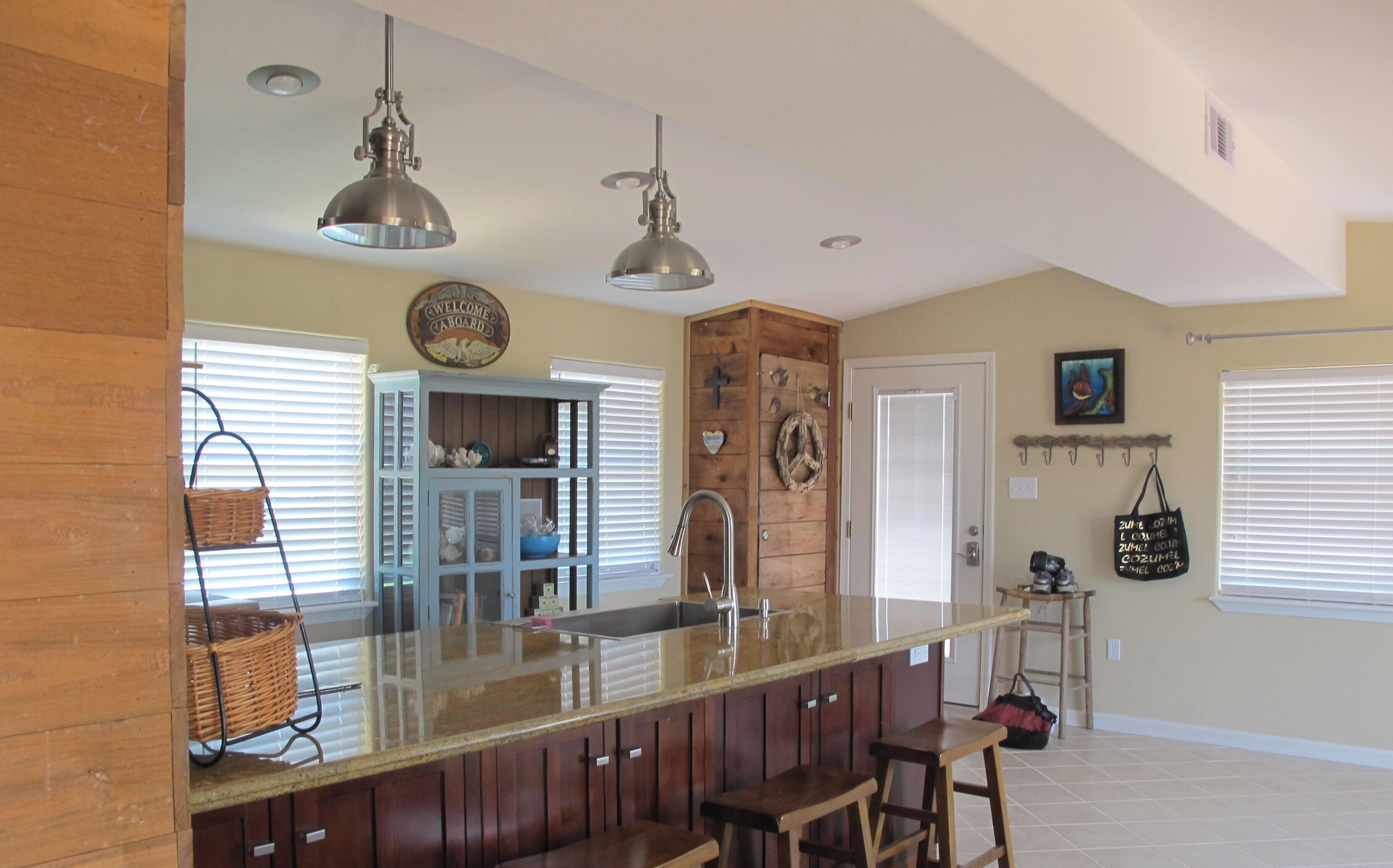 A kitchen with a bar area, wooden cabinets, and a sink.