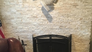 A room with a stone wall, a fireplace, a leather chair, and a mounted bird sculpture. - Dog Friendly, Allergen-free 5 minute walk to the bay and eateries (Los Osos -Baywood Park)