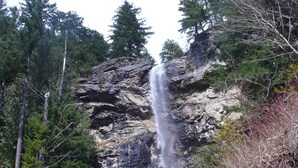 A natural waterfall in a forested area with rocky terrain and trees. - Cascade Mountain Getaway (Rockport)