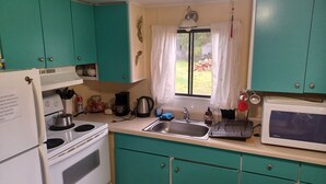 A compact kitchen with teal cabinets, a white refrigerator, a stove, a microwave, and a sink. - Cascade Mountain Getaway (Rockport)