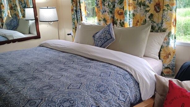 A bedroom with a large bed, floral curtains, a mirror, and a bedside lamp. - Cascade Mountain Getaway (Rockport)