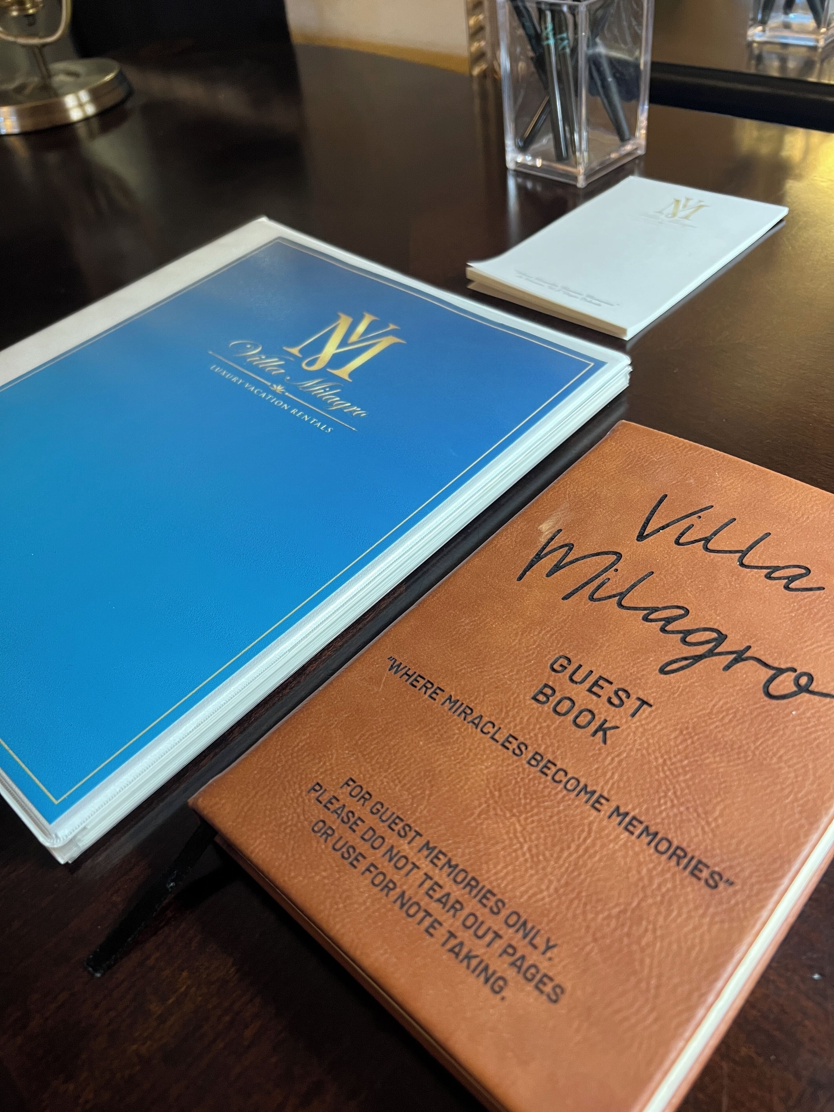 A blue and brown guest book with the name 'Villa Vilagro' on a wooden table.