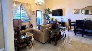 A spacious living room with a high ceiling, a chandelier, a television, and a dining area with a table and chairs. - Newly Updated! Private Beach Views, Luxury Villa Milagro Villa 1 (St.Thomas U.S.V.I)