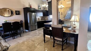 A spacious kitchen with dark cabinetry, a stainless steel refrigerator, and a dining area with a wooden table and chairs. - Newly Updated! Private Beach Views, Luxury Villa Milagro Villa 1 (St.Thomas U.S.V.I)