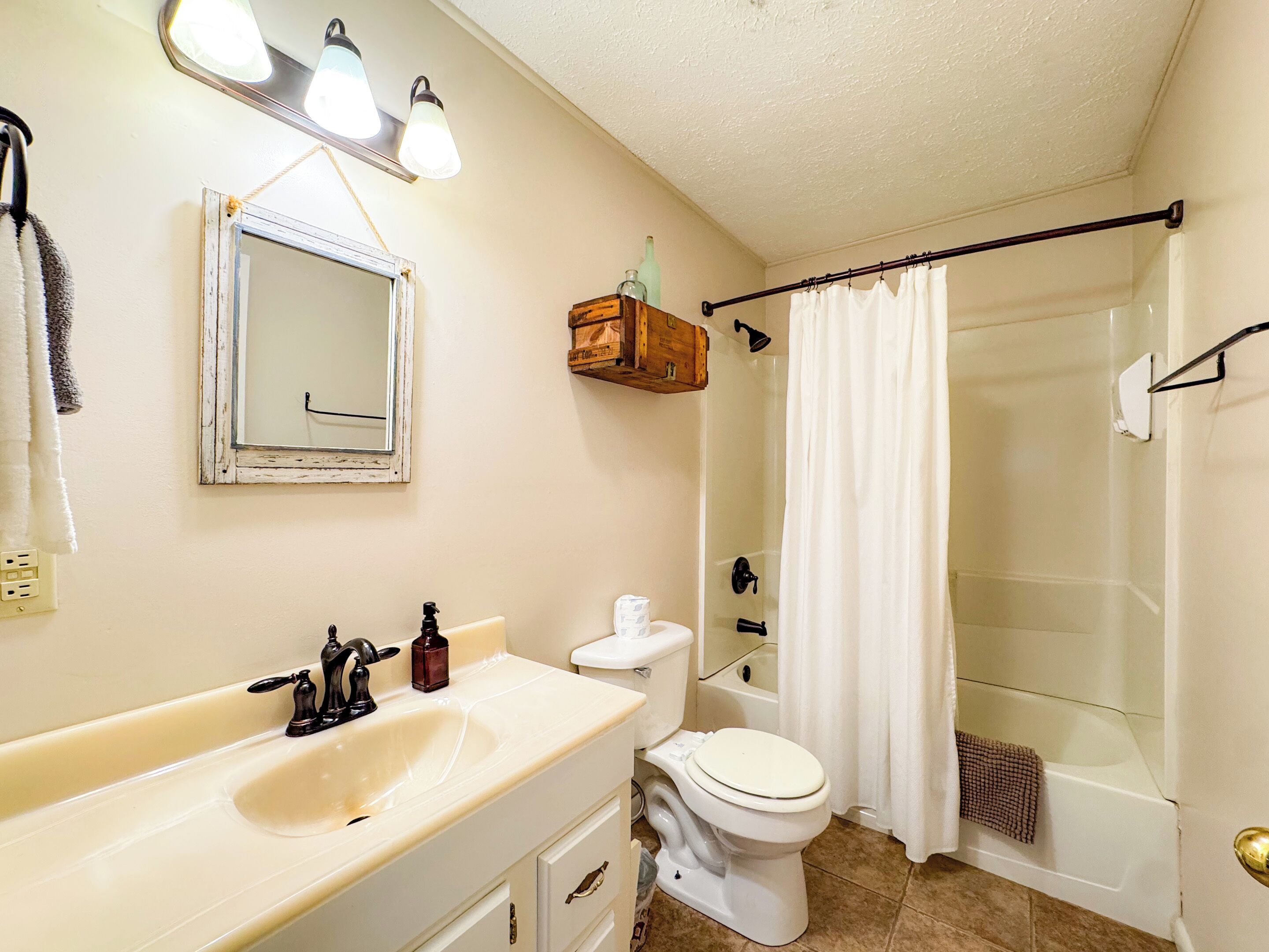 A bathroom with a sink, toilet, and shower area.