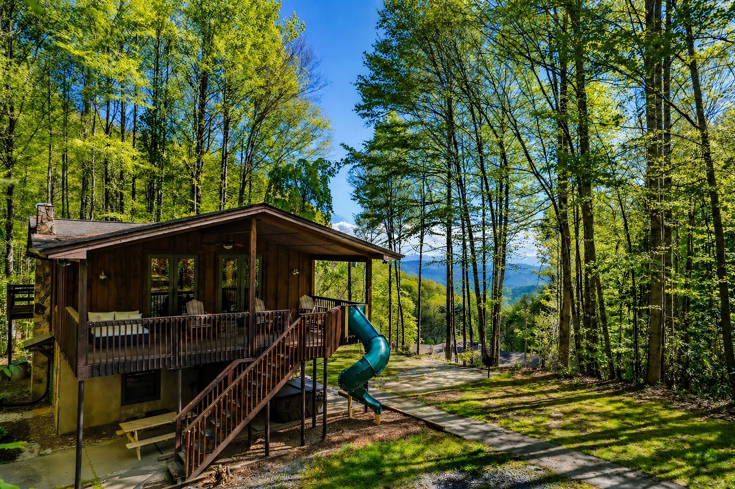 Een chalet met een terras, een glijbaan en uitzicht op een bebost gebied.