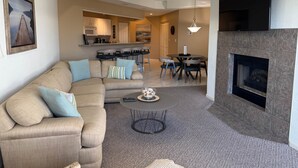 Ein Wohnzimmer mit Sofa, Couchtisch, Kamin und Fernseher.