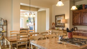 A kitchen with a granite countertop, wooden chairs, a gas stove, and a dining table. - Sun-e-Scape- Relax in the Desert! (Washington)