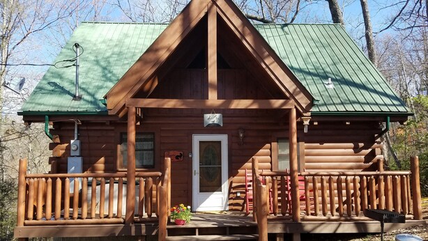 A wooden cabin with a green roof, a porch with wooden railings, and a door with a window above it. - Enjoy Secluded Mountain Paradise at the Rustic Fox! (Sevierville)