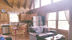 A cozy cabin interior with a dining area, a sofa, and a coffee table. - Enjoy Secluded Mountain Paradise at the Rustic Fox! (Sevierville)