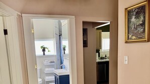 A hallway with a wooden floor, a white door, a blue cabinet, a bathroom with a white toilet, and a framed picture on the wall. - #2 UAB 2bd2bth in the heart of city (Birmingham)