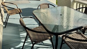 A covered outdoor seating area with wicker chairs and a glass table, overlooking a street with parked cars and buildings. - #2 UAB 2bd2bth in the heart of city (Birmingham)