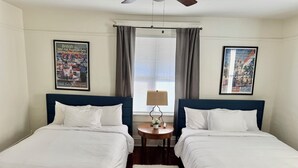 A hotel room with two single beds, a small round table with a lamp, a white rug, and two framed pictures on the walls. - #2 UAB 2bd2bth in the heart of city (Birmingham)