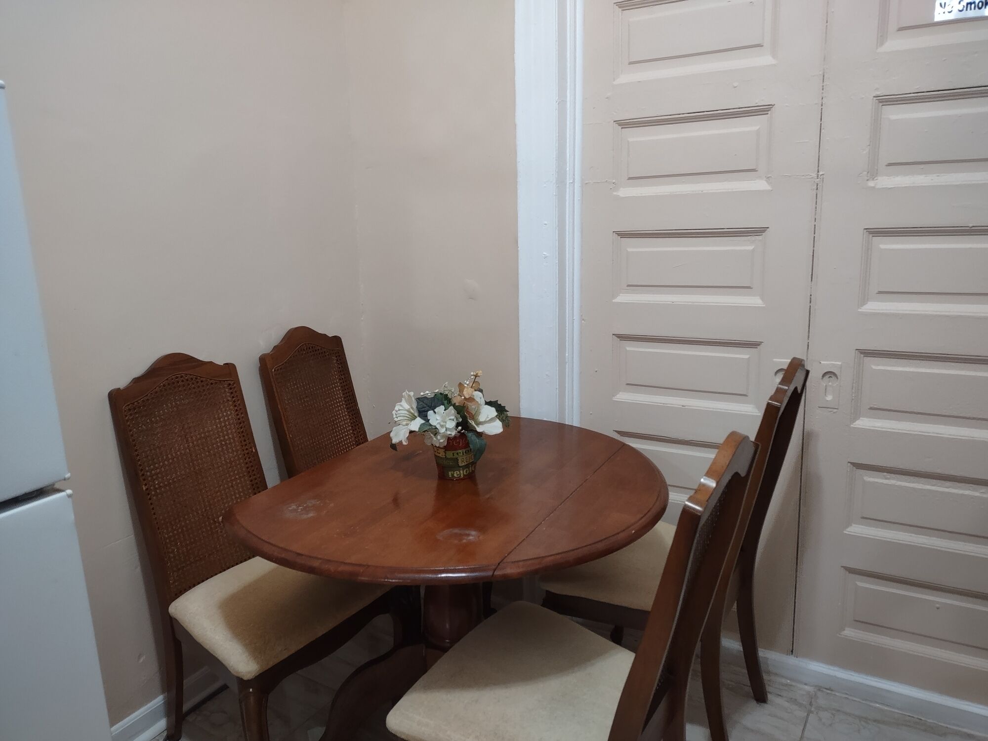 Un coin repas avec une table ronde en bois, quatre chaises et un vase rempli de fleurs.
