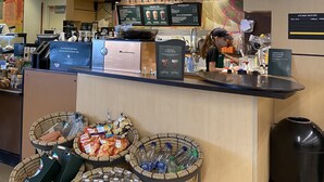 Intérieur d’un café Starbucks, avec une machine à café, des panneaux affichant le menu et un comptoir de caisse.