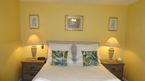 A neatly made bed with white linens, two bedside lamps, and a nightstand with a tissue box.
