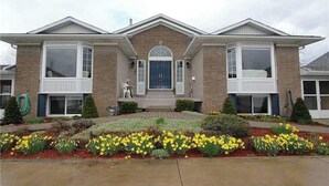 A two-story house with a symmetrical facade, a central entrance with a blue door, and a brick exterior.
