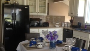 A modern kitchen with white cabinets, a black refrigerator, and a dining area set for a meal.