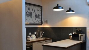 Een moderne keuken met een centraal eiland, hangende lampen en een dakraam.