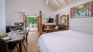 Une pièce spacieuse avec un grand lit, un coin repas comprenant une table et des chaises, un téléviseur et une vue sur l’extérieur par une fenêtre.