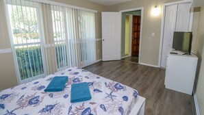 A bedroom with a bed, a television, and a sliding door leading to another room. - 3/2 Home Heated Pool / close to Beautiful Anna Maria Beaches / close to IMG (Bradenton)