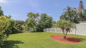 A well-maintained backyard with a lawn, a small tree, and a white fence. - 3/2 Home Heated Pool / close to Beautiful Anna Maria Beaches / close to IMG (Bradenton)