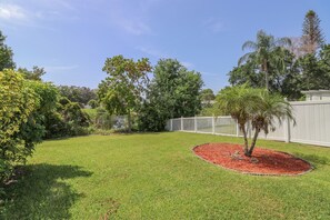 A well-maintained backyard with a lawn, a small tree, and a white fence. - 3/2 Home Heated Pool / close to Beautiful Anna Maria Beaches / close to IMG (Bradenton)