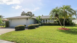 A single-story house with a garage, a well-maintained lawn, and a palm tree. - 3/2 Home Heated Pool / close to Beautiful Anna Maria Beaches / close to IMG (Bradenton)