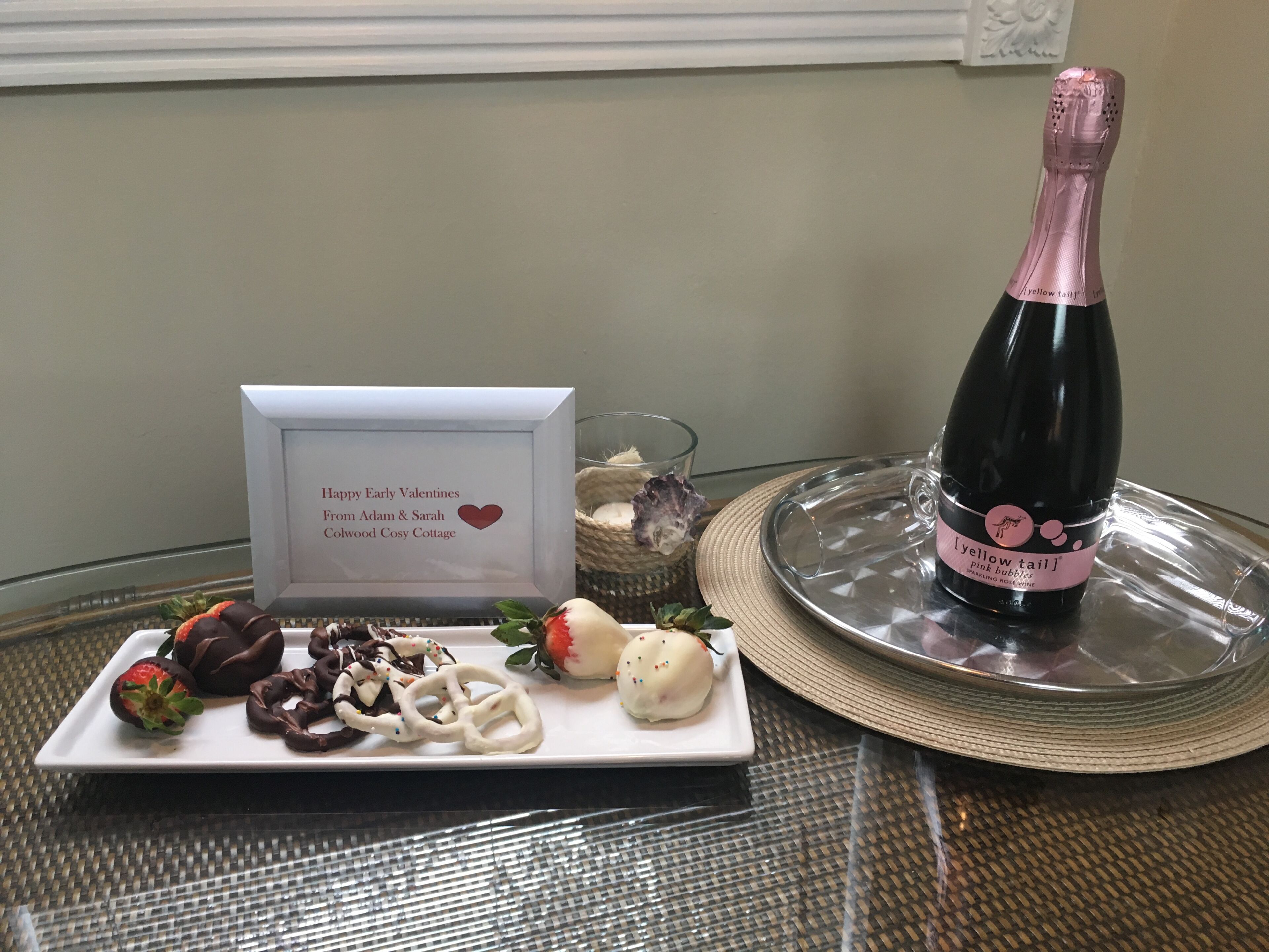 A table with a plate of food, a bottle of champagne, a glass, and a card.
