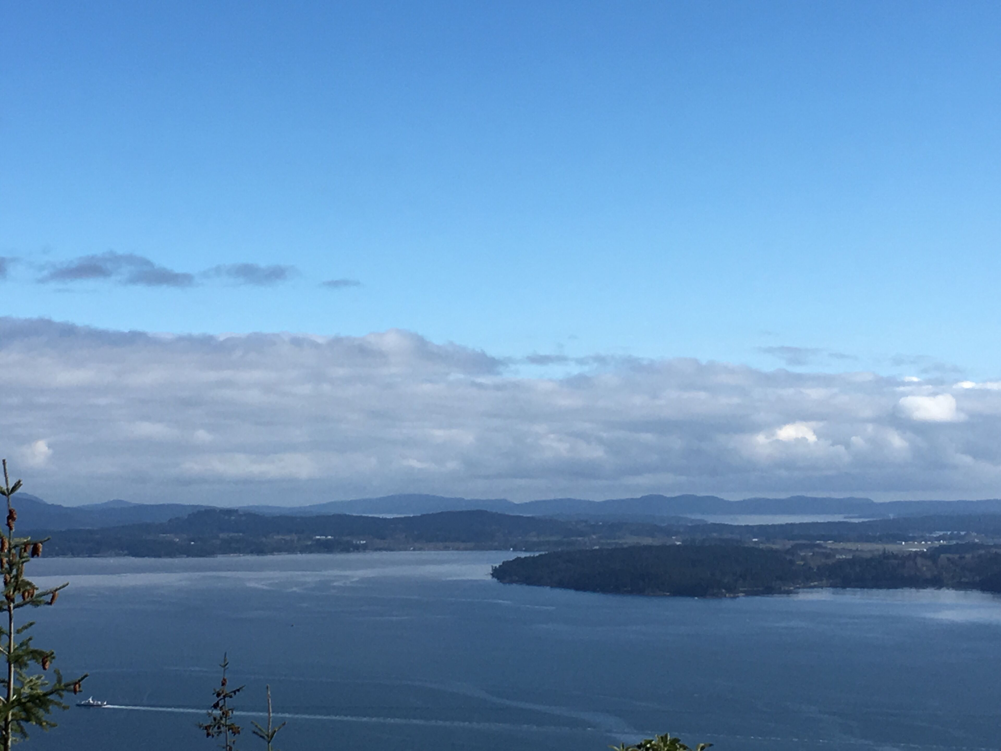Eine Küstenlandschaft mit blauem Himmel, ruhiger See und fernen Bergen.