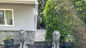 Two lion statues in front of a house with a stone pathway leading to a wooden door.