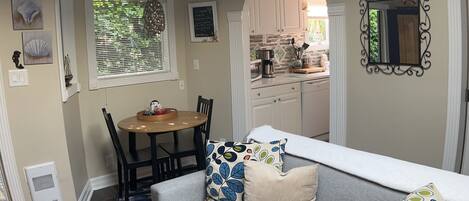 A compact living space with a grey sofa, a dining table, and a kitchen area.