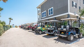 A row of golf carts parked in front of a building with a balcony. - Fully Remodeled Bright and Beautiful  2bed 2 bath condo just steps to the Beach (Murrells Inlet)