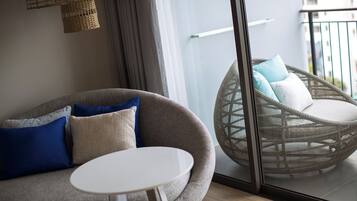 Un salón moderno con un sofá gris, una mesa redonda blanca y una silla de mimbre con cojines.