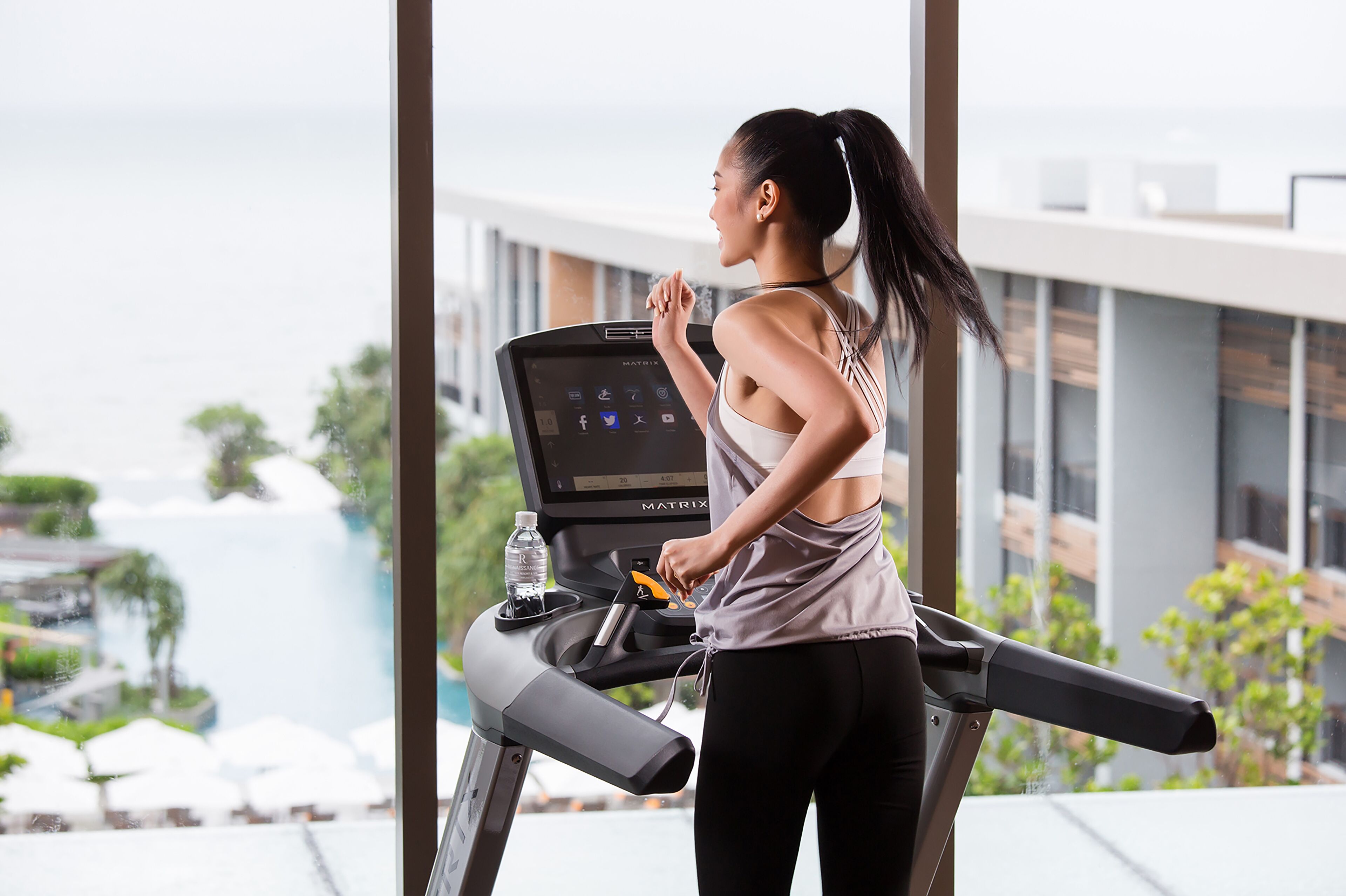 A treadmill with a digital display, water bottle, and a person exercising.
