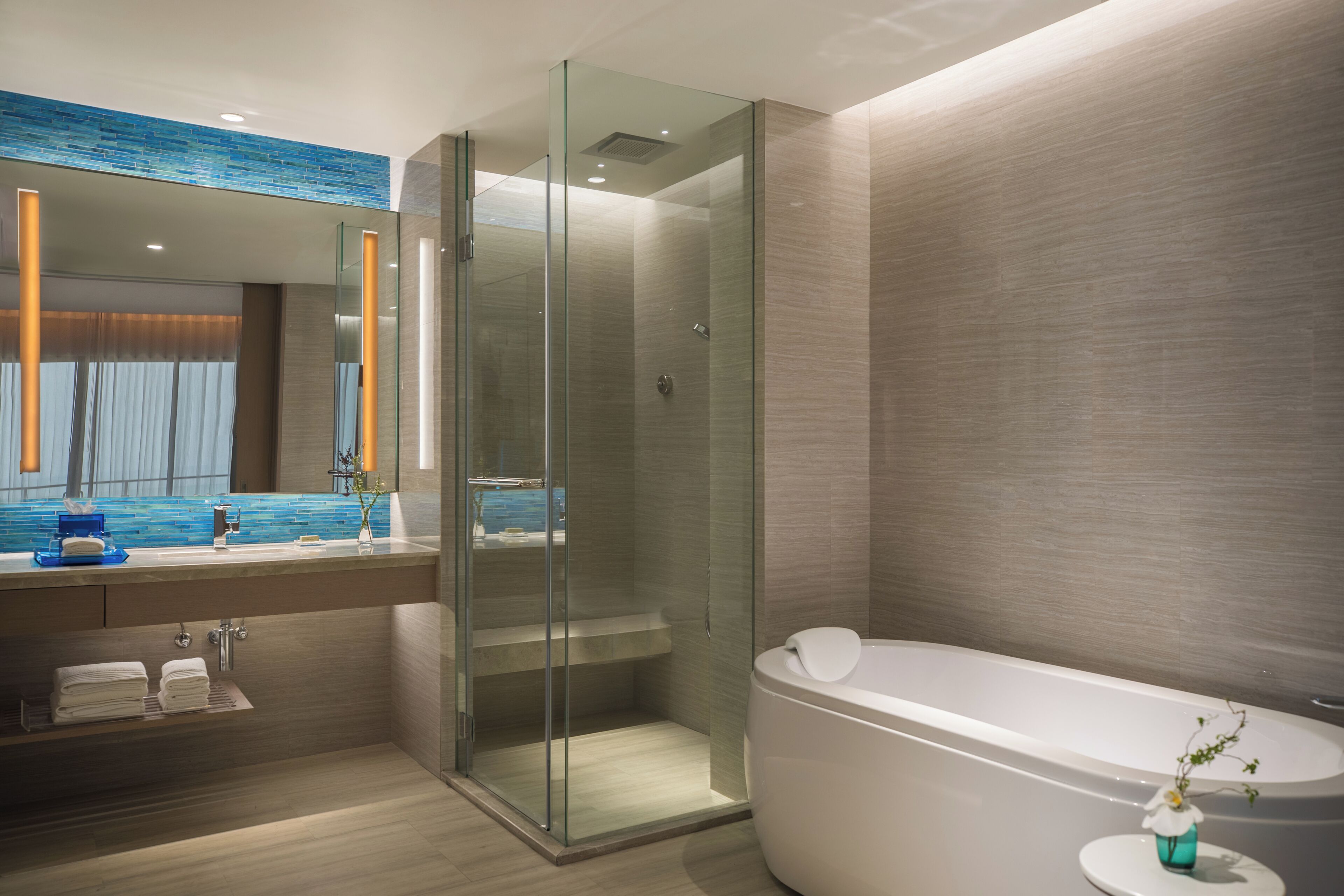 A modern bathroom with a glass-enclosed shower, a large bathtub, and a vanity with a mirror.